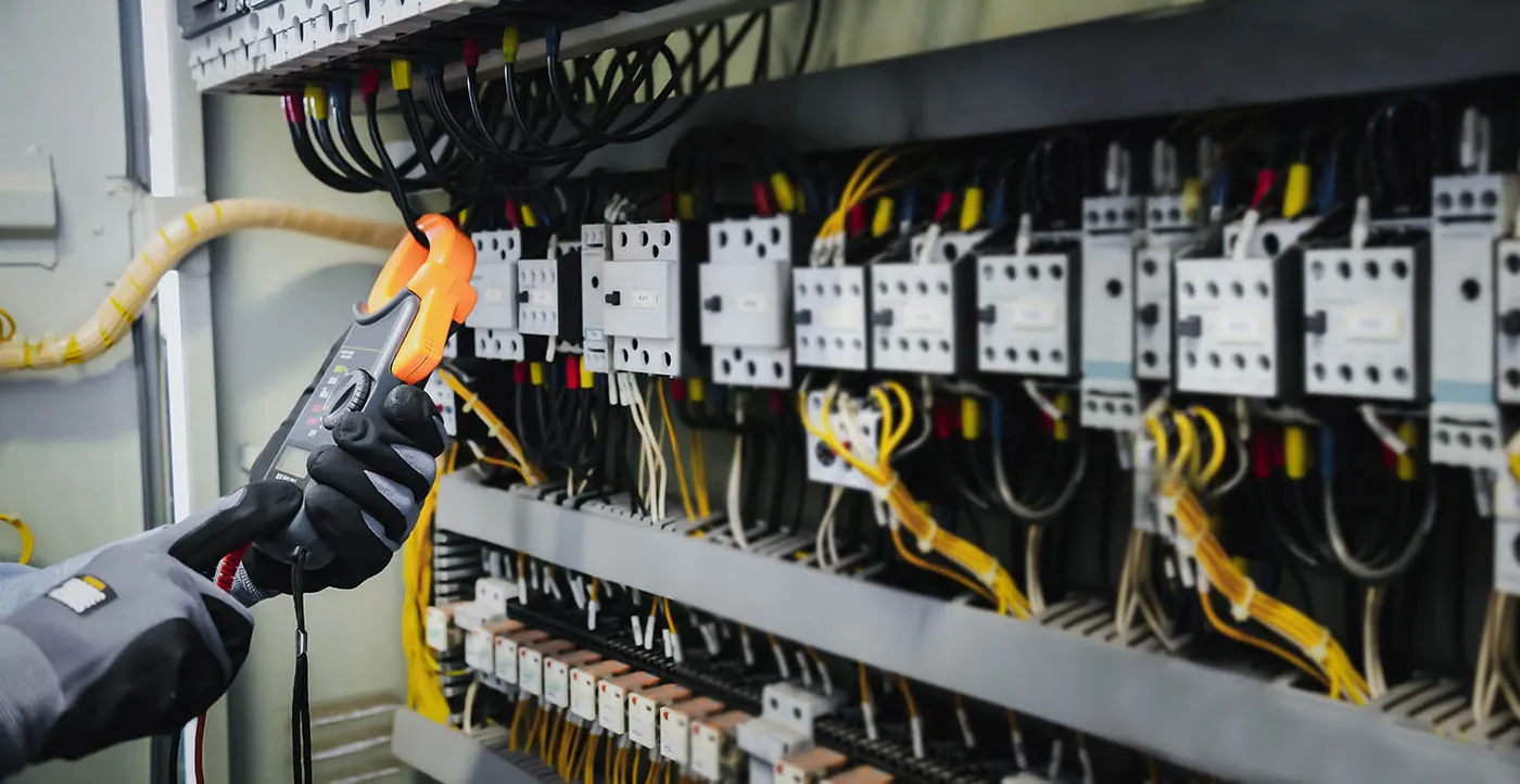 Electrician testing a distribution board with a clamp meter – electrical services in Weston-super-Mare